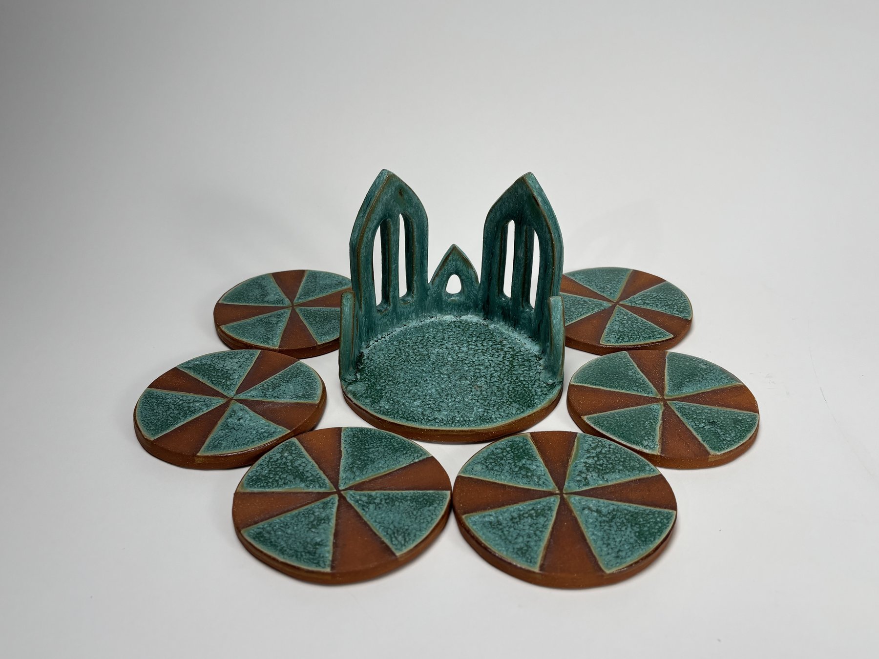 Twin-arch coaster holder with pinwheel coasters fanned out