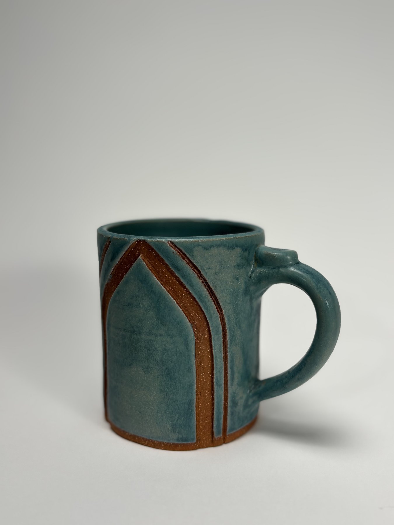 Teal mug with carved arch and clay lines